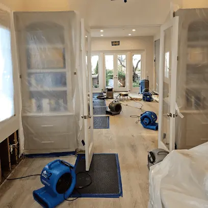 Air movers and a dehumidifier drying a hallway under plastic containment in a Mission Viejo home