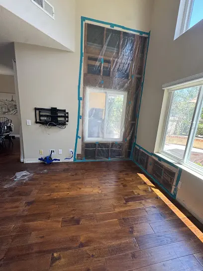 Hardwood floor drying beside a wall opened for air flow in an Orange County two-story home