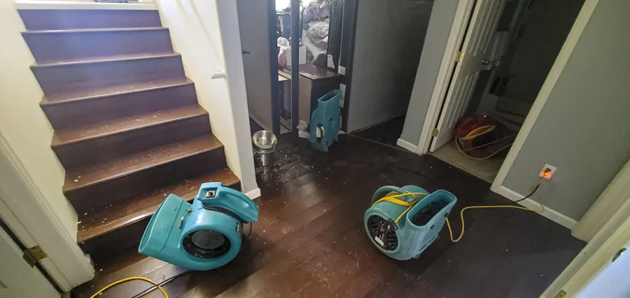 Air movers drying the floor at the foot of a staircase in a two-story Mission Viejo home