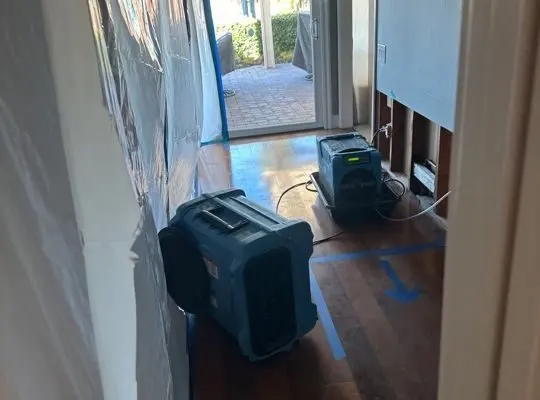 Dehumidifier and air mover drying a hallway beside a sliding door in Mission Viejo