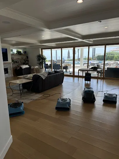 Air movers drying a living room floor in a Mission Viejo home with windows looking out over the valley