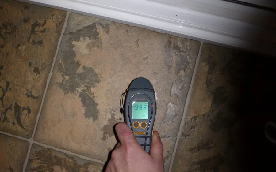 Moisture meter reading a wet tile floor over a concrete slab