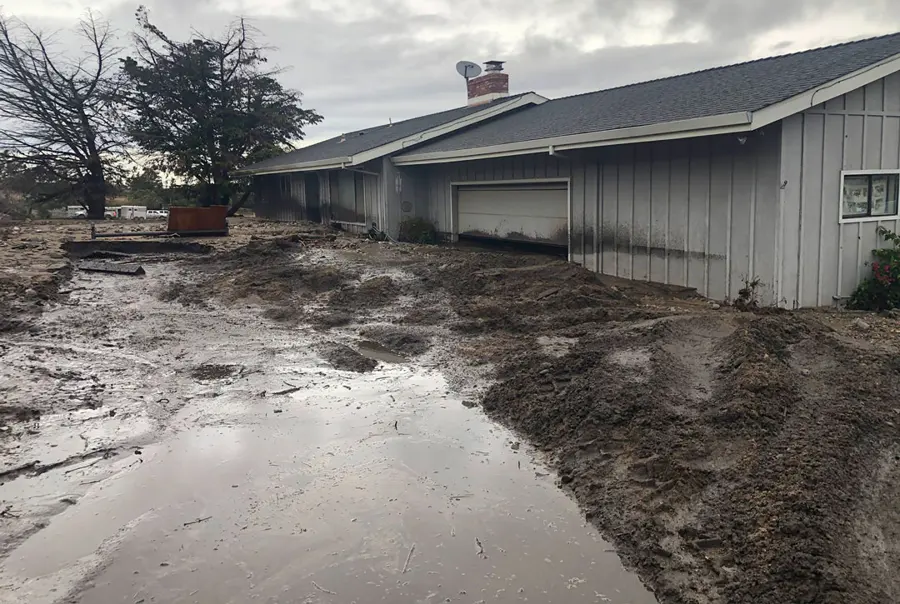 Muddy storm runoff pooled along a single-story house after a heavy California rain