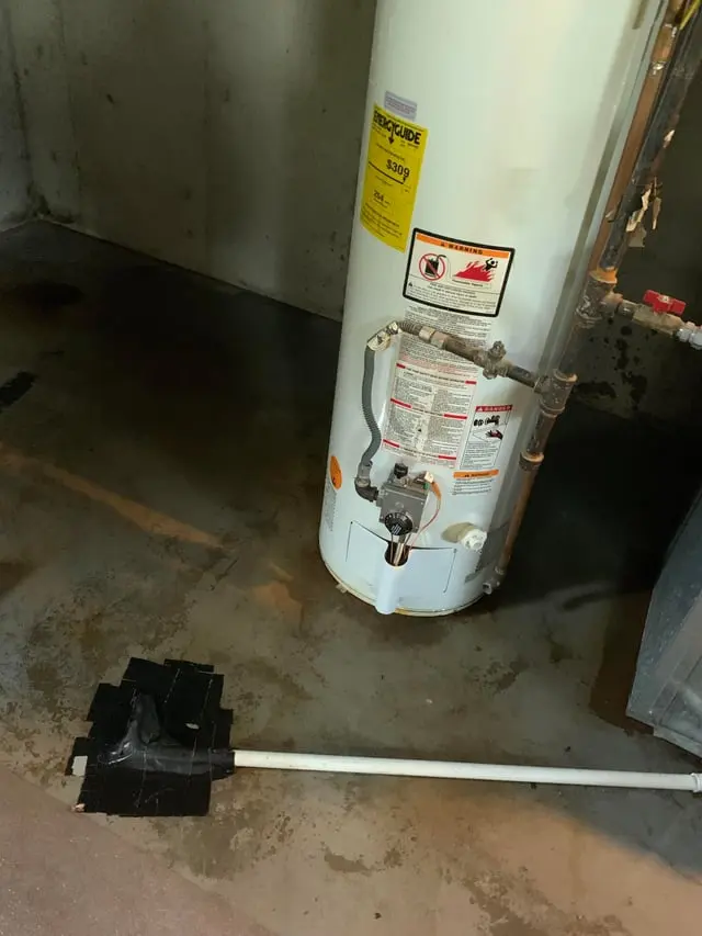 Water pooled around the base of a failed tank water heater in a Mission Viejo garage